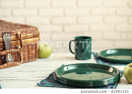 Wooden basket for picnic with plates, cups and silverware close up Wooden basket for picnic with plates, cups and silverware close up 82401581