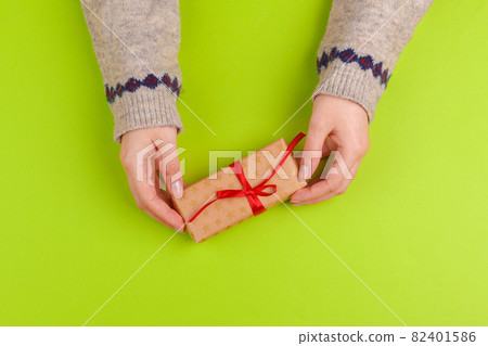Woman hands holding gift box on green background 82401586