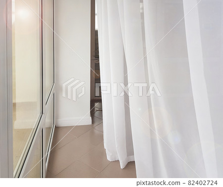 Side view of a huge panoramic window with a transparent white curtain, modern interior of apartments in a luxury hotel 82402724