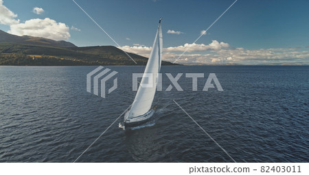 Closeup yacht race at ocean shore with green mountains. Seascape with luxury ship under white sails Closeup yacht race at ocean shore with green mountains. Seascape with luxury ship under white sails 82403011