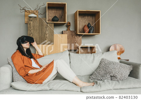A young woman wearing virtual reality glasses, a headset, a VR box. The girl is trying to touch objects in virtual reality. A young woman wearing virtual reality glasses, a headset, a VR box. The girl is trying to touch objects in virtual reality. 82403130