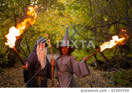 Wizard and sorceress in the autumn forest. Elderly man and woman in carnival costumes for halloween Wizard and sorceress in the autumn forest. Elderly man and woman in carnival costumes for halloween 82404309