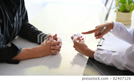 Doctor showing patient's temperature on digital thermometer Doctor showing patient's temperature on digital thermometer 82407126