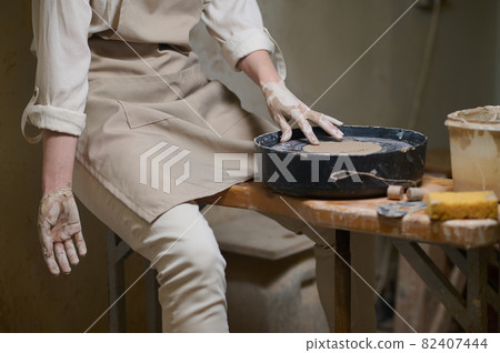 A female potter in her workshop looking involved in the process of pottery A female potter in her workshop looking involved in the process of pottery 82407444