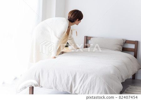 A woman who wakes up in the morning and makes a bed A woman who wakes up in the morning and makes a bed 82407454