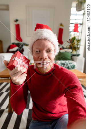 Albino african american man wearing santa hat making video call with christmas decorations 82408190