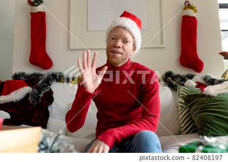 Albino african american man wearing santa hat making video call with christmas decorations 82408197