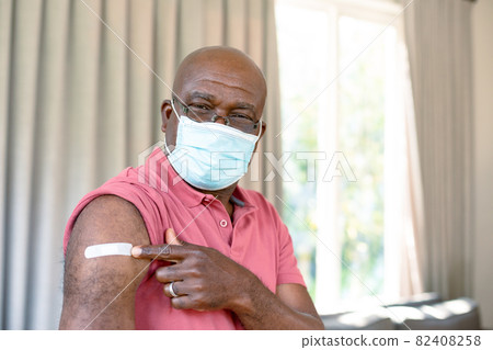 Senior african american man in face mask showing plaster after vaccination Senior african american man in face mask showing plaster after vaccination 82408258
