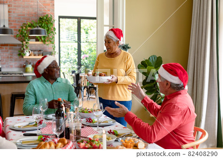 Diverse group of happy senior friends in holiday hats celebrating christmas together at home 82408290