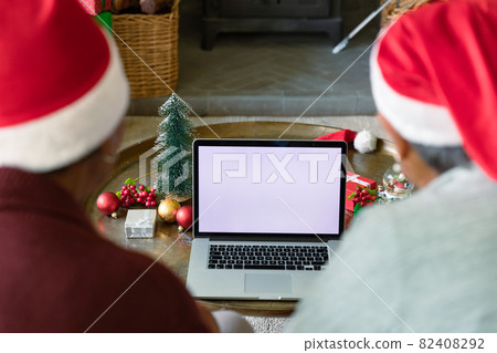 Two diverse senior female friends wearing santa hats using laptop with copy space at christmas time Two diverse senior female friends wearing santa hats using laptop with copy space at christmas time 82408292