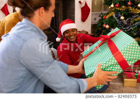 Happy diverse female and male friends sharing presents at christmas time 82408373