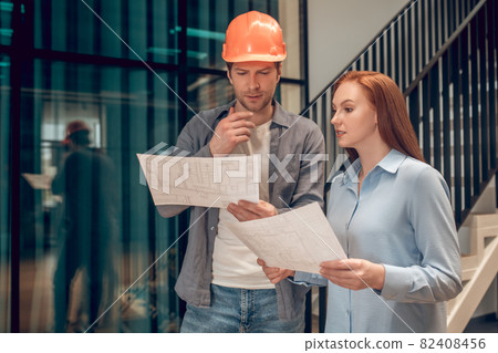 Two young employees discussing construction plan Two young employees discussing construction plan 82408456