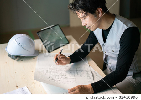 Male worker checking the drawing Male worker checking the drawing 82410990