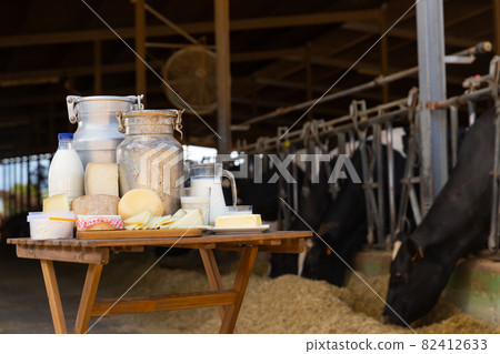 Dairy products - milk, cheese, cottage cheese on the background of cows in barn Dairy products - milk, cheese, cottage cheese on the background of cows in barn 82412633