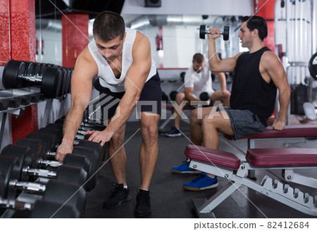 Man choosing dumbbells at gym 82412684