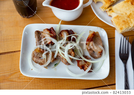 Grilled pork shashlyk with onions and satsebeli sauce Grilled pork shashlyk with onions and satsebeli sauce 82413033