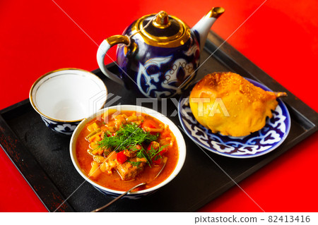 Uzbek laghman, samsa, teapot and cup on tray 82413416