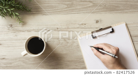 The person who writes notes on the material on the table 82417526
