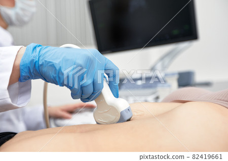 Female doctor gives the patient a female abdominal ultrasound. Ultrasound scanner in the hands of a doctor. 82419661