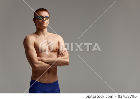 Portrait of a swimmer in a cap and mask, half-length portrait, young athlete swimmer wearing a cap and mask for swimming, copies of space, gray background 82419790