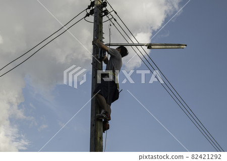 Electrician, repairman are climbing and work on electric pole. 82421292