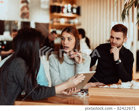 A group of friends hanging out in a cafe, and among them is a tablet. 82422671