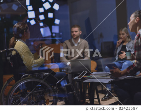 Businesswoman in wheelchair having business meeting with team at modern office Businesswoman in wheelchair having business meeting with team at modern office 82423587