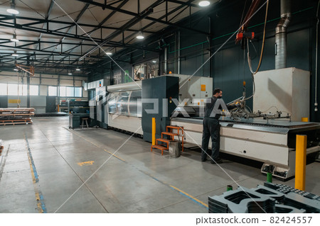 A smart factory worker or engineer wears a face mask because of a pandemic and makes machines in a production workshop. The concept of industry and engineering. A smart factory worker or engineer wears a face mask because of a pandemic and makes machines in a production workshop. The concept of industry and engineering. 82424557