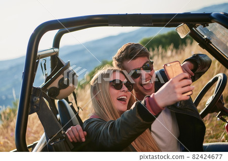 couple enjoying beautiful sunny day taking selfie picture while driving a off road buggy couple enjoying beautiful sunny day taking selfie picture while driving a off road buggy 82424677