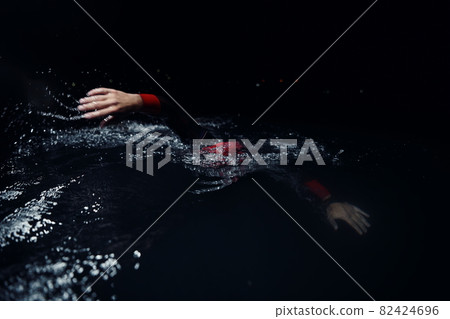 triathlon athlete swimming in dark night wearing wetsuit 82424696