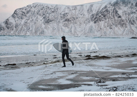 Arctic surfer going by beach after surfing Arctic surfer going by beach after surfing 82425033
