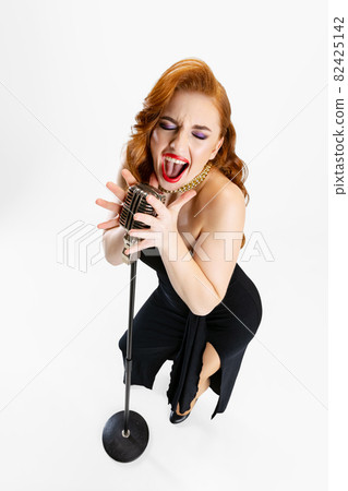 Top view full-length portrait of beautiful red-haired woman singing in microphone isolated over white background Top view full-length portrait of beautiful red-haired woman singing in microphone isolated over white background 82425142
