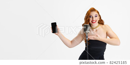 Cropped portrait of beautiful woman in stylish black dress poiting at phone screen isolated over white background. Flyer Cropped portrait of beautiful woman in stylish black dress poiting at phone screen isolated over white background. Flyer 82425185