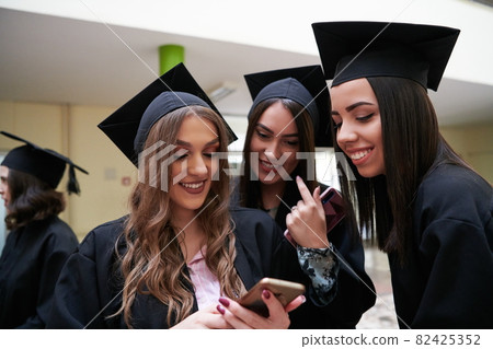 students in mortar boards using smartphone students in mortar boards using smartphone 82425352