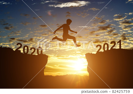 Silhouette of young man jump between 2020 and 2021 years, over the sunset and through gap of hill Silhouette of young man jump between 2020 and 2021 years, over the sunset and through gap of hill 82425759