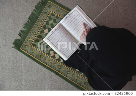 Middle eastern woman praying and reading the holy Quran 82425960