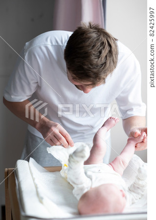 Father changing dirty stinky diaper with yellow poop for his newborn baby Father changing dirty stinky diaper with yellow poop for his newborn baby 82425997