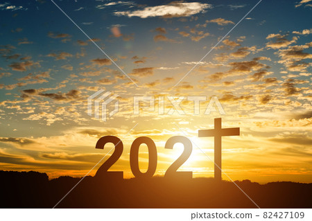 Silhouette of Christian cross with 2021 years at sunset background. 82427109