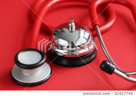 Red medical stethoscope and bell on red background. Medical service appointment 82427748