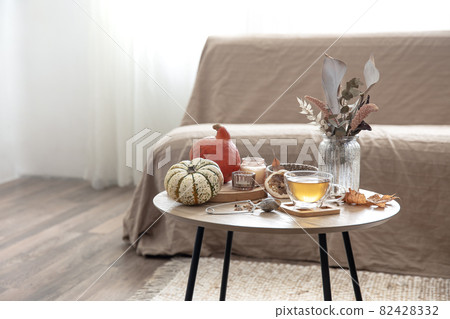 Autumn composition with tea and pumpkins in the interior of the room. 82428332