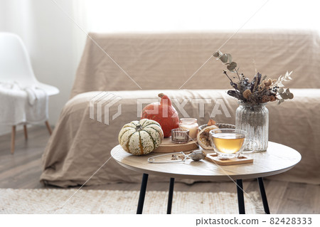 Autumn composition with tea and pumpkins in the interior of the room. Autumn composition with tea and pumpkins in the interior of the room. 82428333
