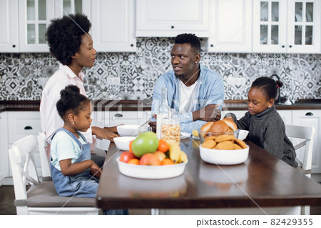African American young parents with two little daughters having breakfast on kitchen 82429355