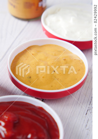 close up of Mustard, mayonnaise and sauce in a container on table . 82429992