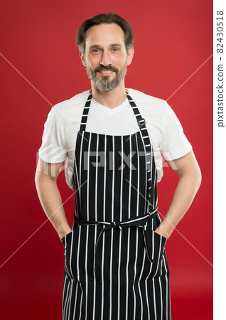Skilled and confident. Senior cook wearing bib apron.  82430518