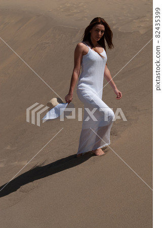 Blonde woman in desert dunes wearing white clothes 82435399