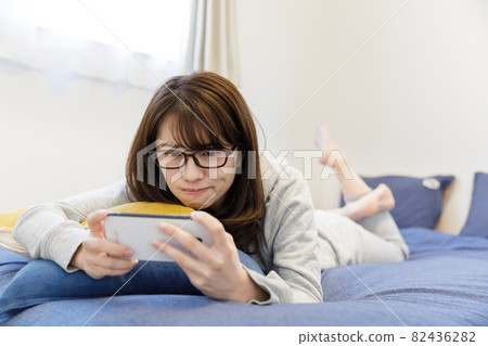 Woman looking at a smartphone on the bed Woman looking at a smartphone on the bed 82436282