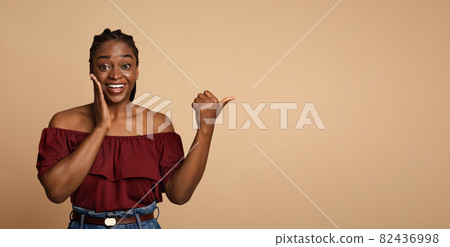 Surprised african american millennial woman pointing at copy space 82436998