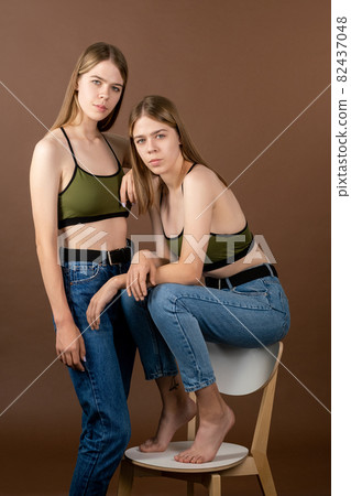Two pretty teenage girls in tanktops and blue jeans 82437048