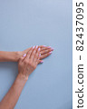 Elegant hands with pink manicure on a blue background, clean color, white skin. 82437095