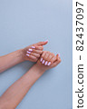 Beautiful women's hands with a pink manicure on a blue background. Top view. Clean skin. 82437097
